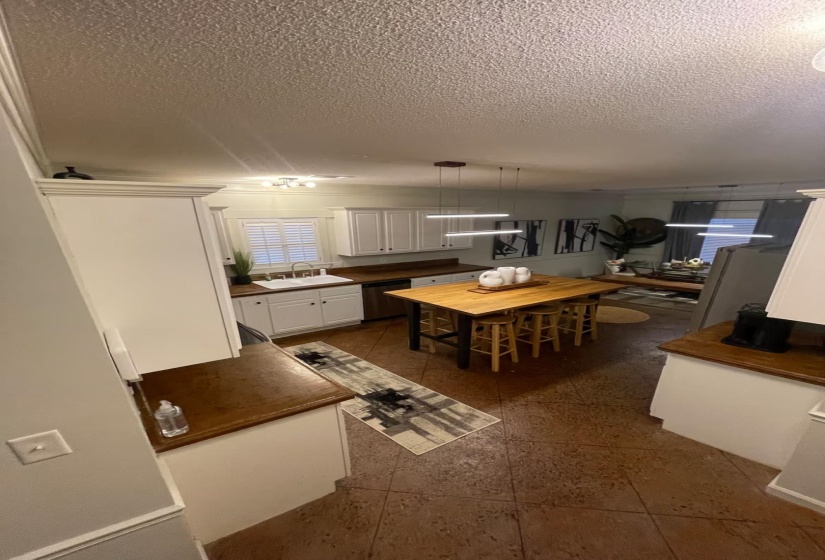 Kitchen with white cabinets, dark countertops, hanging light fixtures, a textured ceiling, and dishwasher