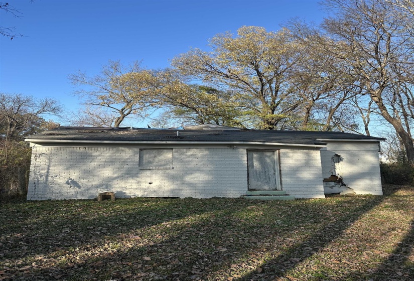 View of side of home with brick siding, a lawn, and a shingled roof