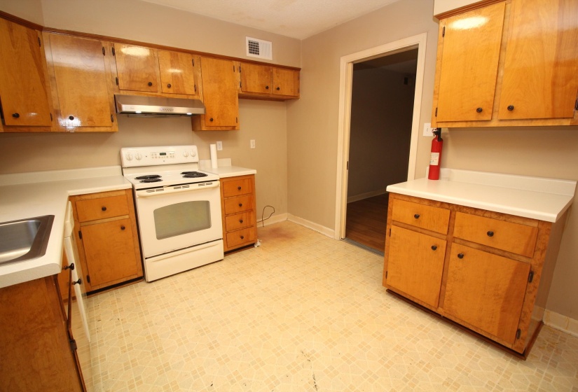 Kitchen featuring light flooring, white electric range, brown cabinetry, light countertops, and under cabinet range hood