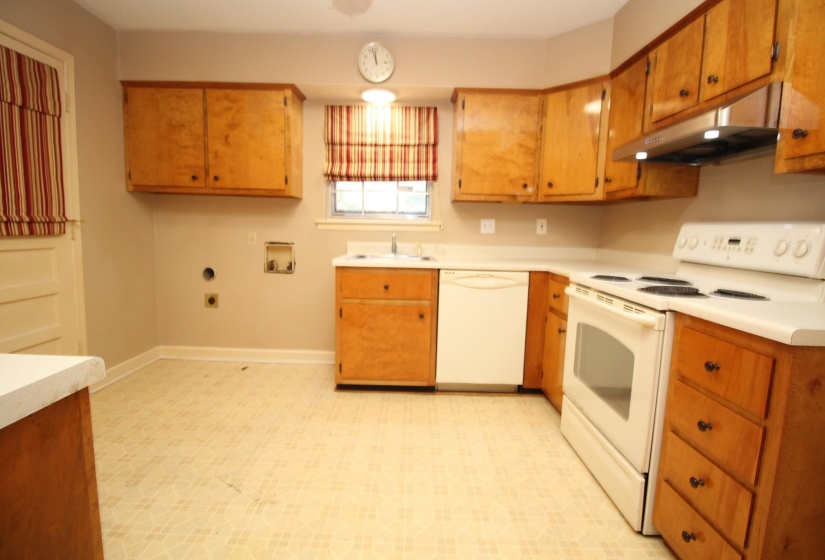 Kitchen with light flooring, white appliances, light countertops, under cabinet range hood, and brown cabinetry