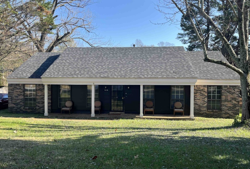 Rear view of house with roof with shingles, a lawn, brick siding, and a patio