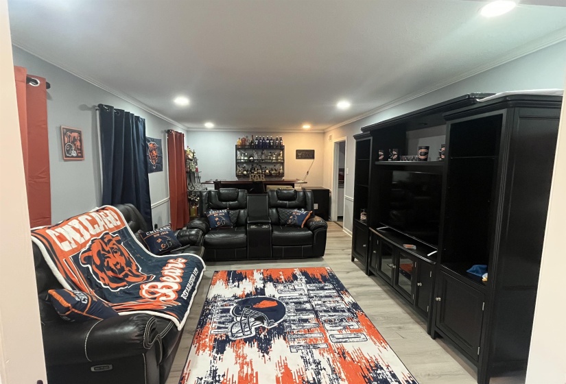 Living area featuring light wood-style flooring, crown molding, a bar, and recessed lighting