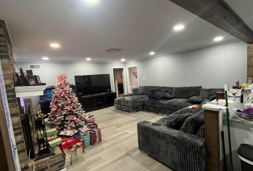 Living area featuring light wood finished floors, a brick fireplace, and wood walls