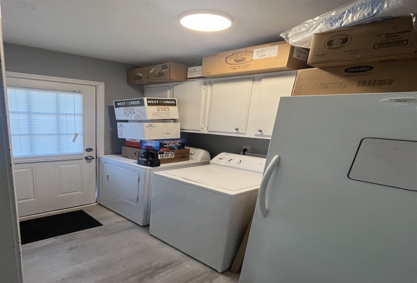Washroom with light wood-type flooring, cabinet space, and washer and clothes dryer