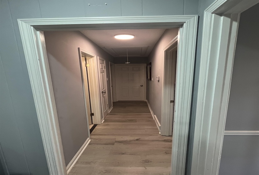 Hallway with attic access and light wood-style flooring