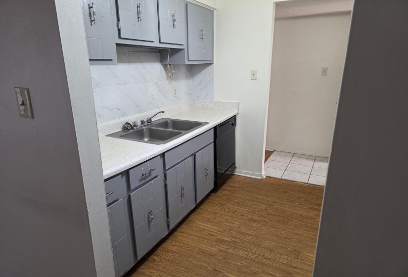 Kitchen with gray cabinetry, tasteful backsplash, light countertops, and dark wood-type flooring