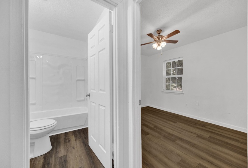 Bathroom featuring dark wood finished floors, a textured ceiling, shower / washtub combination, and ceiling fan
