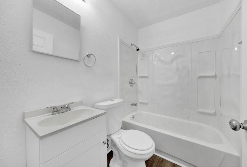Full bath featuring shower / bathtub combination, vanity, and a textured wall