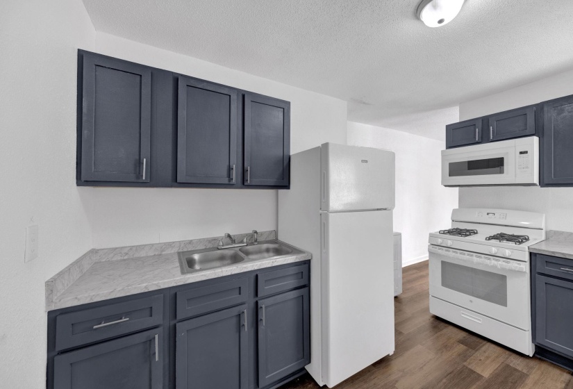 Kitchen with white appliances, dark wood-style flooring, a textured ceiling, and gray cabinets