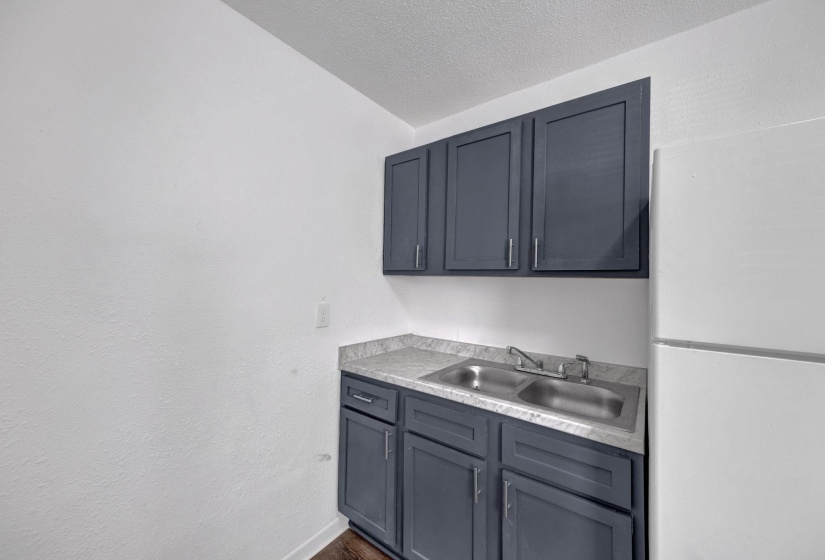 Kitchen featuring freestanding refrigerator, light countertops, gray cabinets, and a textured ceiling