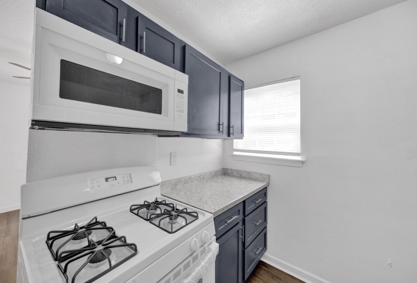 Kitchen featuring white appliances, light countertops, a textured ceiling, dark wood finished floors, and blue cabinetry