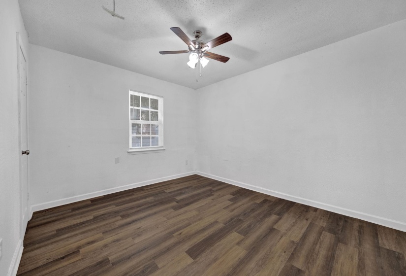 Empty room featuring dark wood-style flooring, a textured ceiling, and a ceiling fan