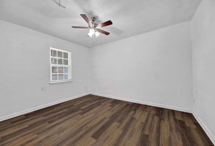 Empty room with dark wood-style floors, a textured ceiling, and ceiling fan