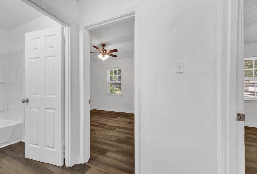 Hall with dark wood-style flooring, healthy amount of natural light, and a textured ceiling