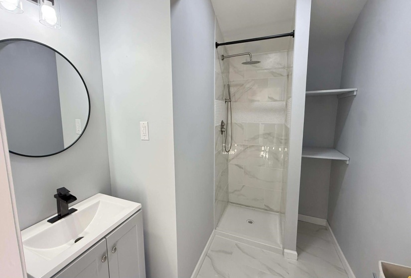 Bathroom with vanity, a marble finish shower, and light marble finish flooring
