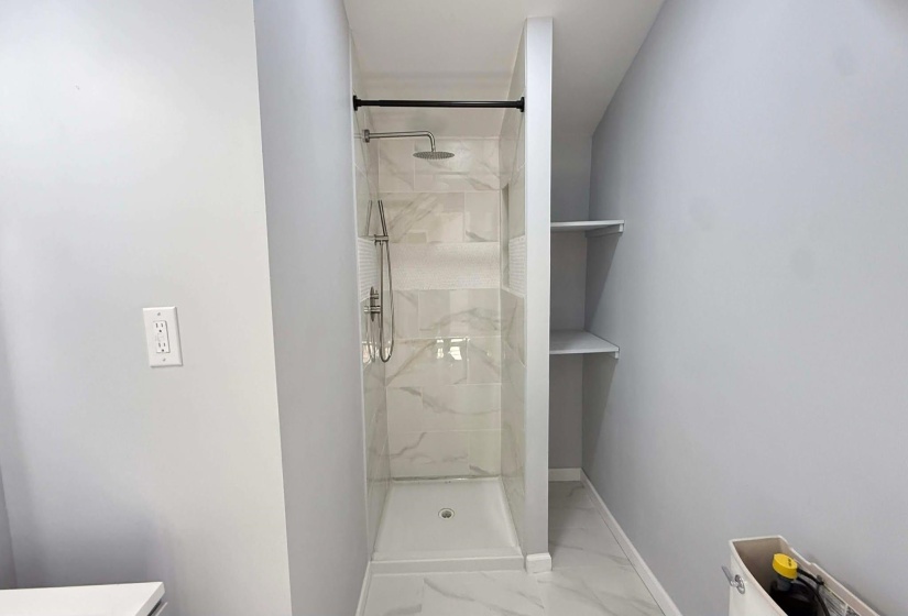 Full bath with a marble finish shower and light marble finish flooring