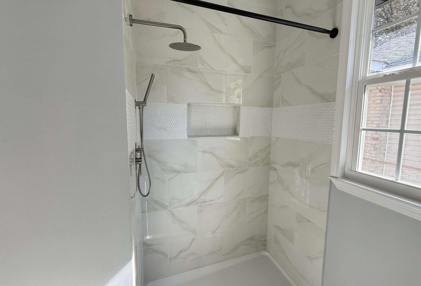 Full bathroom featuring healthy amount of natural light and a marble finish shower