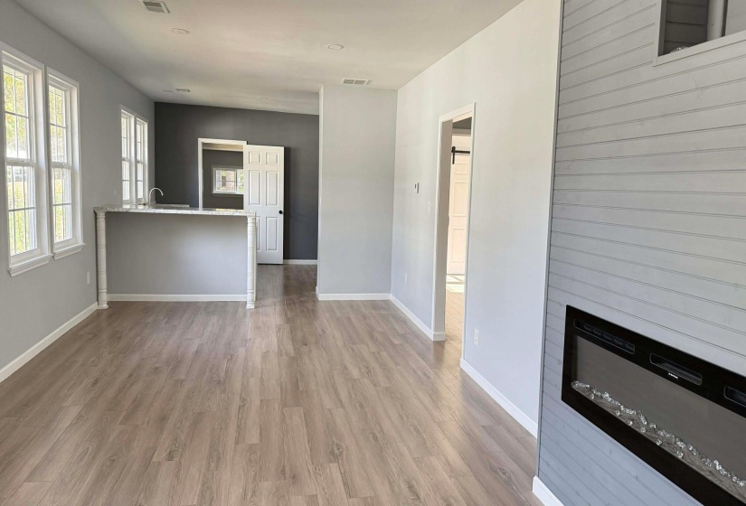 Unfurnished living room with a glass covered fireplace and light wood finished floors