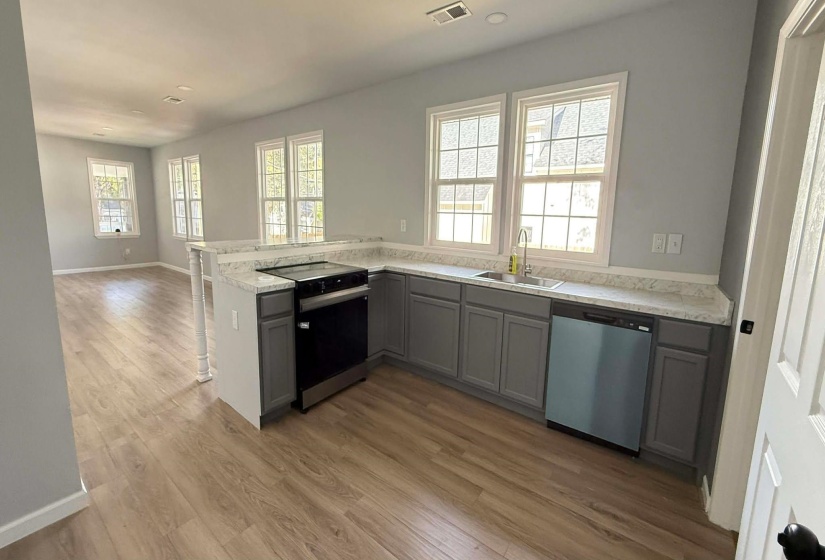 Kitchen featuring light countertops, black / electric stove, stainless steel dishwasher, light wood-type flooring, and a peninsula