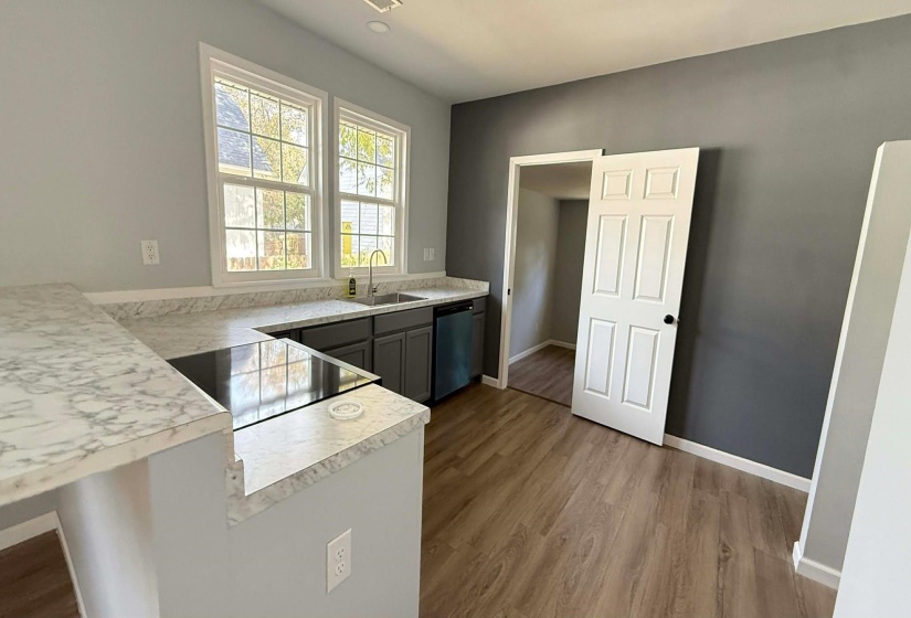 Kitchen with light countertops, a peninsula, light wood-style floors, dishwasher, and black range with electric stovetop
