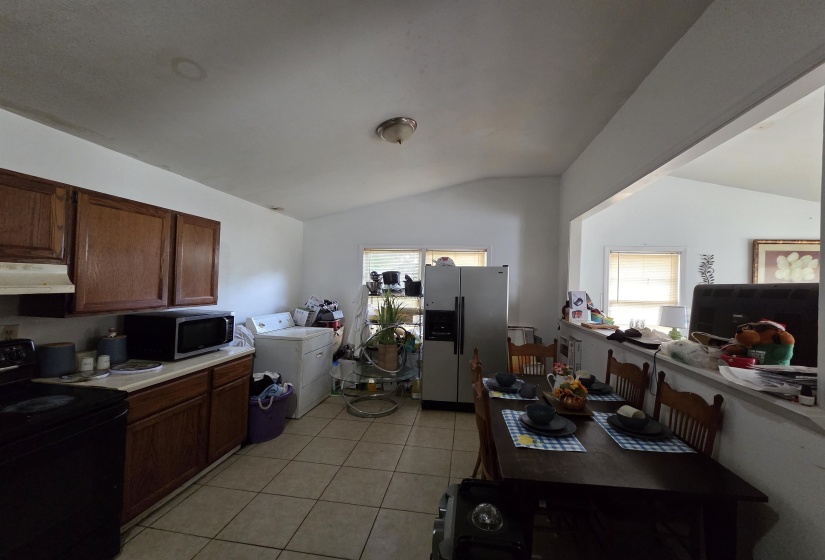 Kitchen featuring appliances with stainless steel finishes, lofted ceiling, light countertops, light tile patterned flooring, and under cabinet range hood