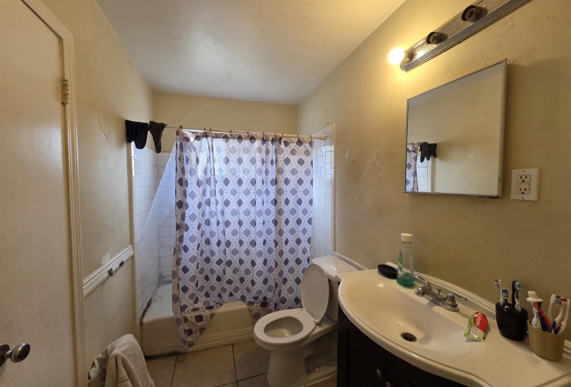 Bathroom featuring shower / tub combo with curtain, vanity, and tile patterned floors