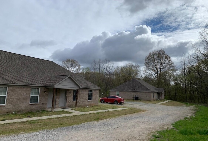 View of side of home featuring brick siding, driveway, and a shingled roof