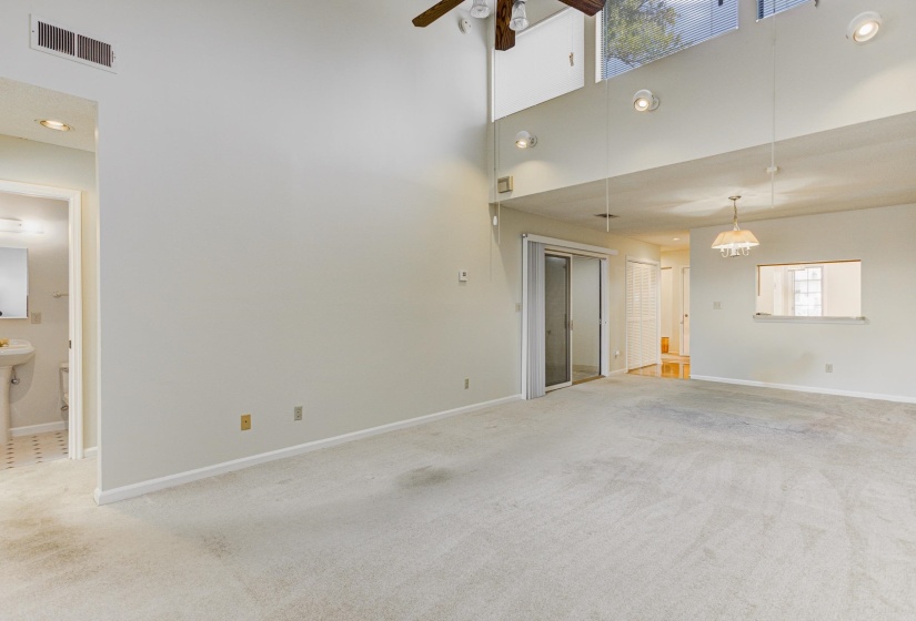 Unfurnished living room featuring light carpet, recessed lighting, a towering ceiling, and a ceiling fan
