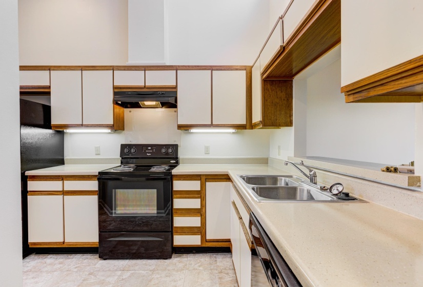 Kitchen featuring black appliances, light countertops, brown cabinetry, and white cabinetry