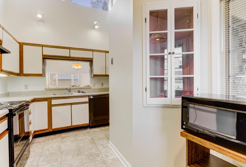 Kitchen featuring brown cabinets, light countertops, white cabinets, and black appliances