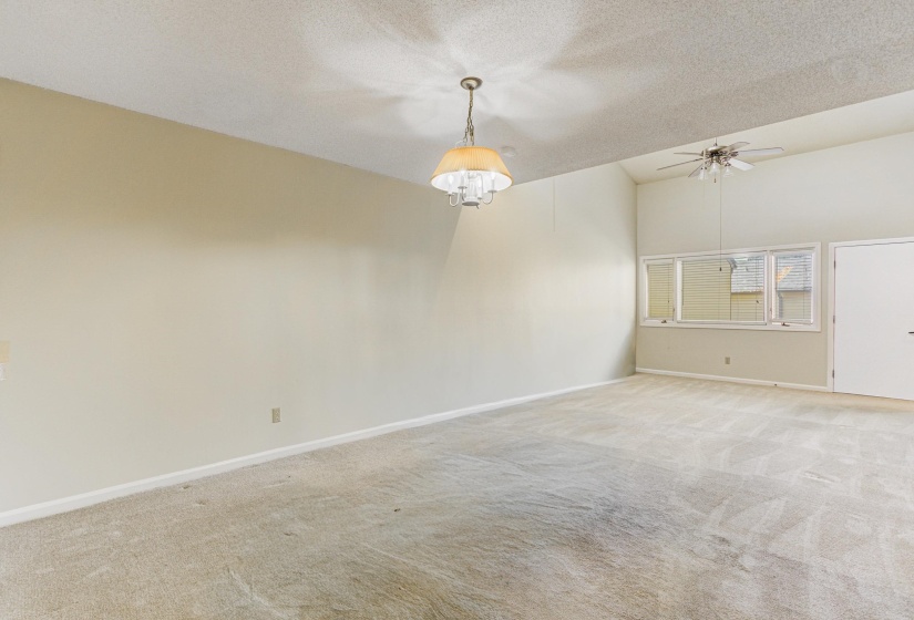 Empty room featuring light colored carpet, a textured ceiling, and a ceiling fan