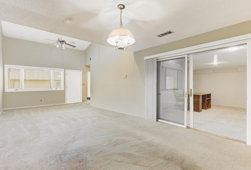 Unfurnished room featuring light colored carpet, a textured ceiling, vaulted ceiling, and a ceiling fan