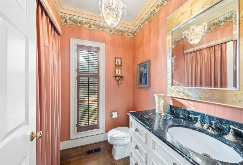 Half bathroom with vanity, a chandelier, dark wood-style flooring, and crown molding