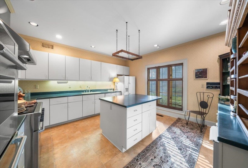 Kitchen with dark countertops, white cabinets, appliances with stainless steel finishes, a center island, and decorative backsplash