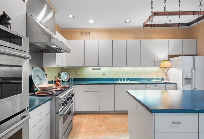 Kitchen featuring dark countertops, stainless steel appliances, exhaust hood, white cabinets, and recessed lighting