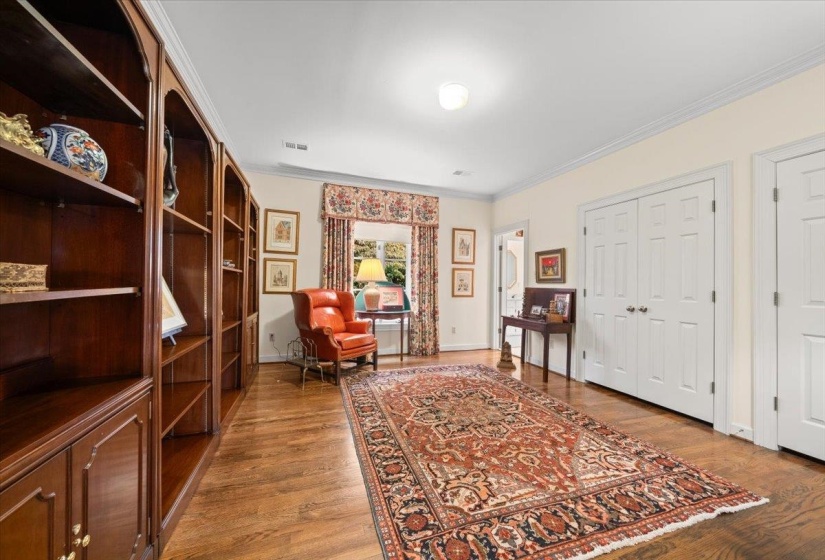 Living area with crown molding and light wood-style floors