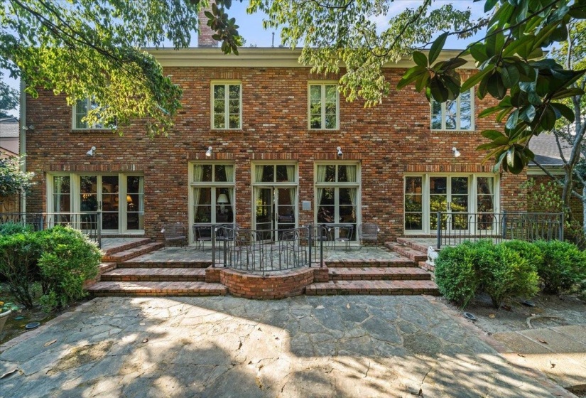 Back of house featuring a chimney, brick siding, and a patio area