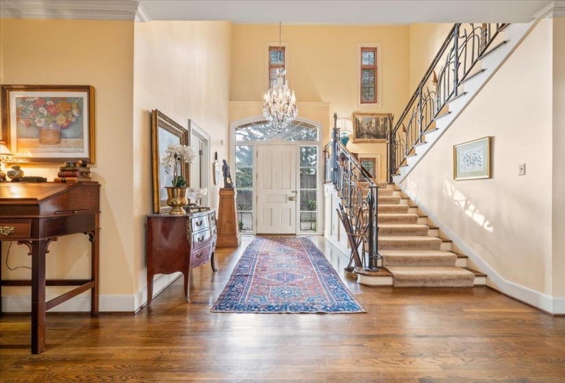 Foyer with a high ceiling, a chandelier, wood finished floors, and stairway