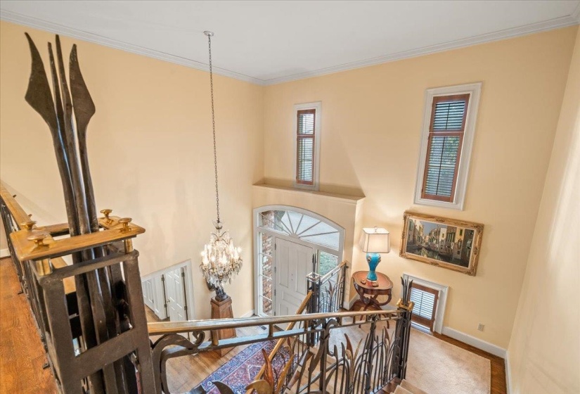 Hallway featuring wood finished floors, a high ceiling, an upstairs landing, a chandelier, and ornamental molding