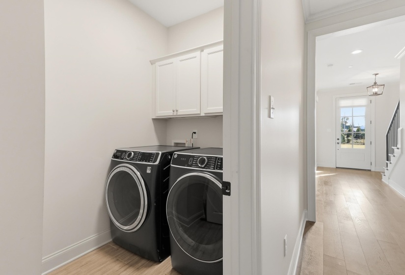 Laundry room with light wood-type flooring, washing machine and clothes dryer, cabinet space, and recessed lighting