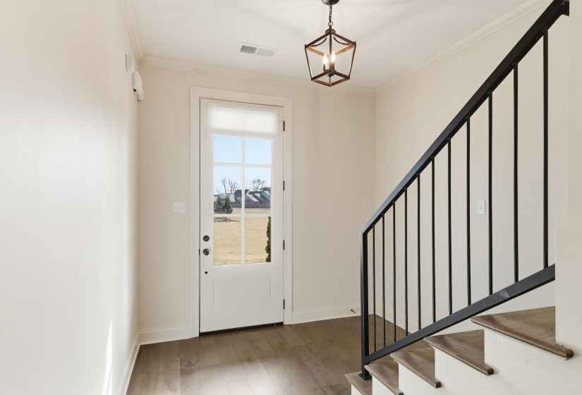 Foyer featuring stairs, crown molding, and wood finished floors