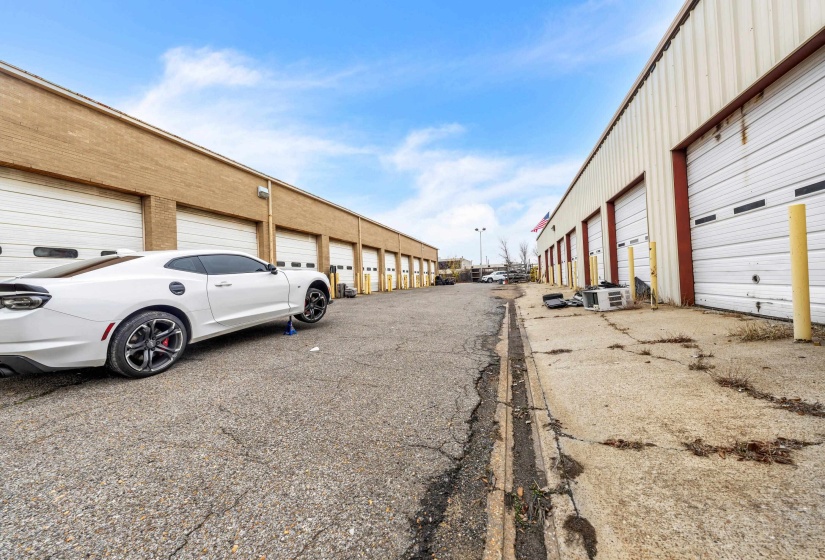 View of asphalt alley featuring community garages
