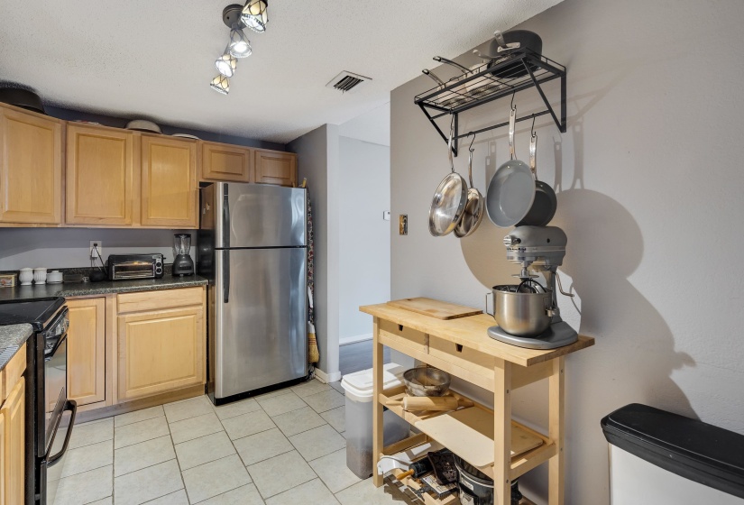 Kitchen with freestanding refrigerator, black electric range oven, and light tile patterned floors