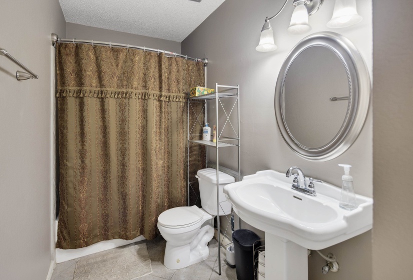 Bathroom featuring light tile patterned floors, a textured ceiling, and shower / bath combination with curtain