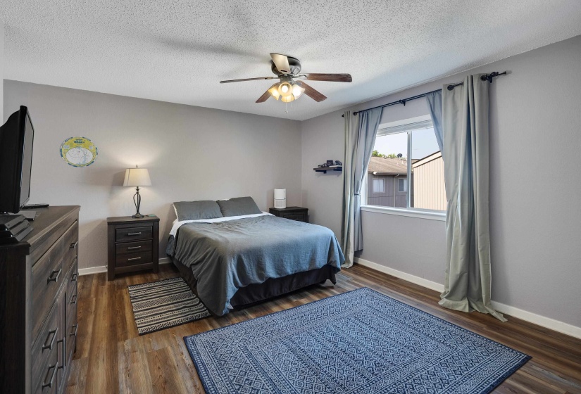 Bedroom with a textured ceiling, dark wood-type flooring, and a ceiling fan