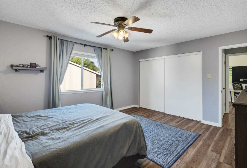Bedroom with wood finished floors, a ceiling fan, a textured ceiling, and a closet