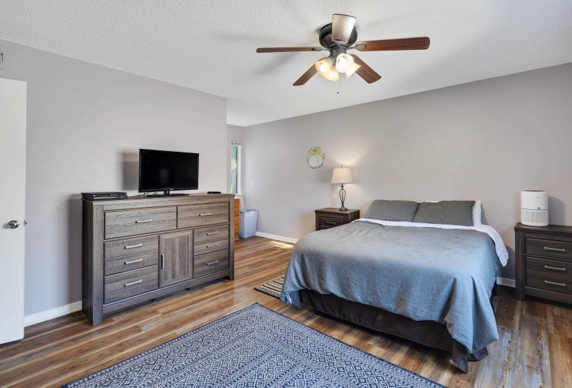Bedroom with ceiling fan, light wood-type flooring, and a textured ceiling