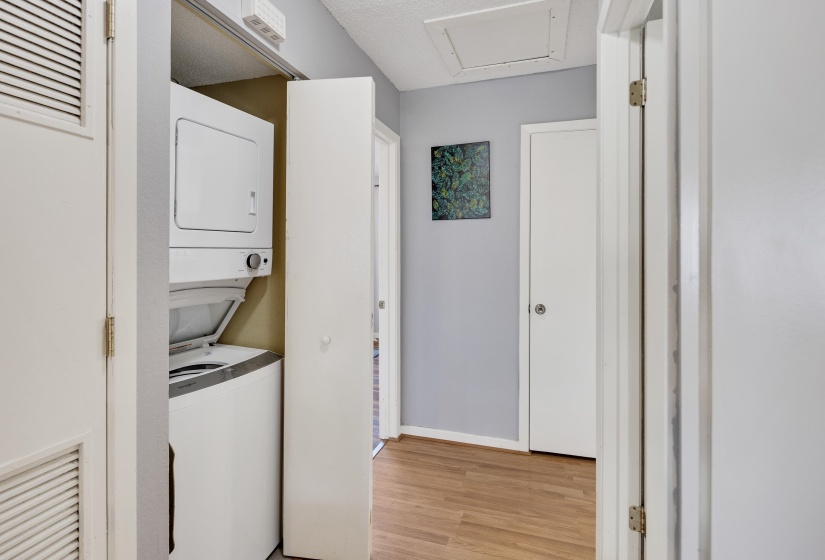 Laundry area with stacked washer / dryer and light wood-type flooring