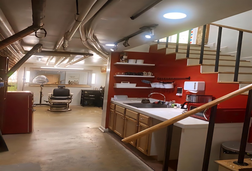 snack area with open shelves, sink, concrete flooring, light countertops and freestanding refrigerator.