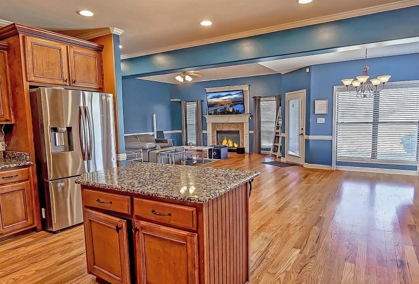 Kitchen featuring dark stone counters, brown cabinets, light wood finished floors, recessed lighting, and ornamental molding